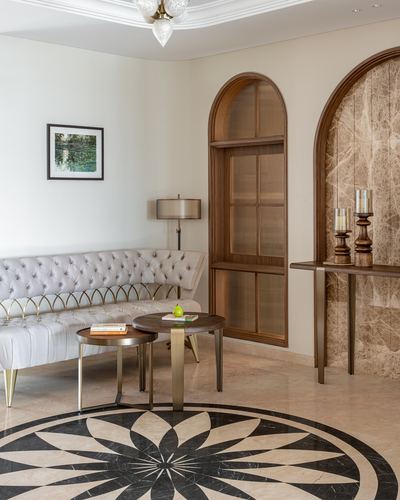 Living room corner with tufted sofa, round marble medallion floor, arched wood niche and stone console