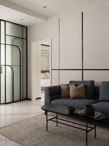 Minimalist living room with charcoal sofa, black coffee table, and fluted glass sliding door