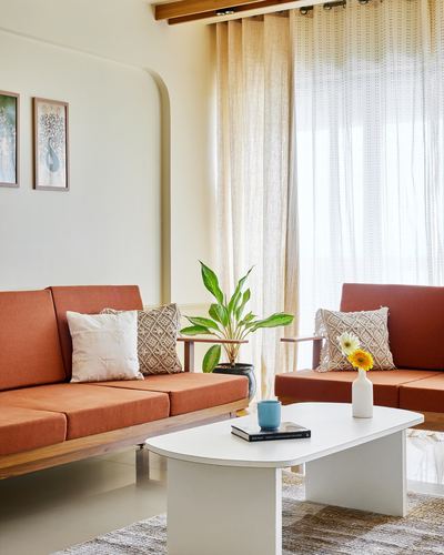 Living room with terracotta sofas, sheer curtains and white oval coffee table in daylight