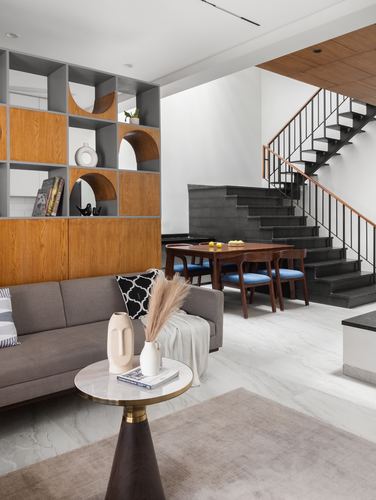 Living room with arched shelving unit, marble side table, and staircase leading up beyond dining area