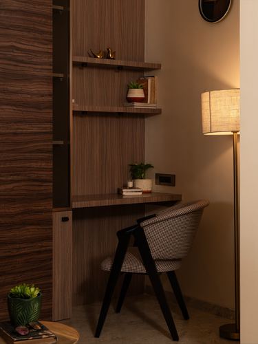 Wood-paneled study nook with floating shelves, desk, houndstooth chair, and brass floor lamp