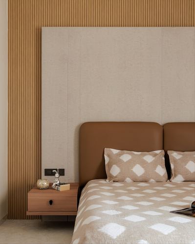 Bedroom corner with fluted wood wall, textured plaster panel, and tan leather headboard bed