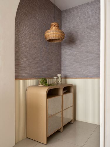 Curved wooden sideboard in an arched foyer niche with a woven pendant light overhead