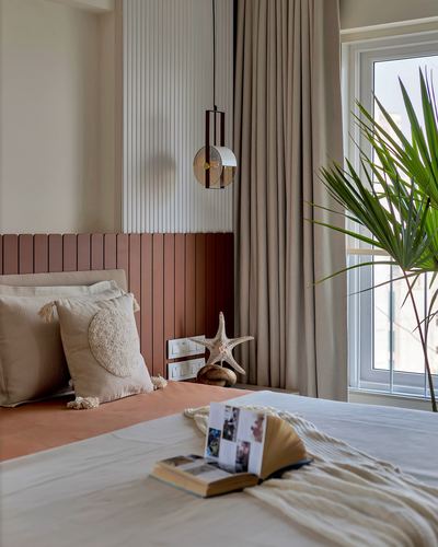 Bedroom with terracotta fluted headboard, round pendant light, and large window with plant
