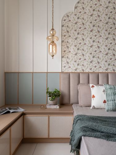 Bedroom corner with channel-tufted headboard, floral wallpaper arch, wood paneling, and amber pendant light