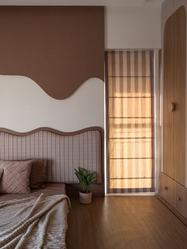 Bedroom with wavy brown accent wall, checkered headboard, and warm afternoon light through a woven blind