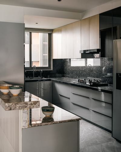 Modern U-shaped kitchen with glossy grey cabinetry, dark stone counters and a marble-look island in foreground