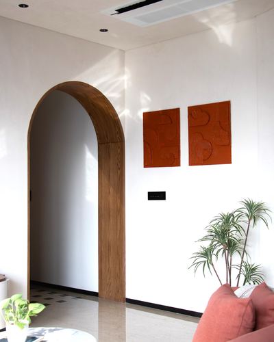 White foyer with wooden arched doorway, terracotta wall panels, and marble floor in sunlight