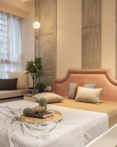 Bedroom with pink velvet headboard, wood paneled wall, and styled bench seating by window