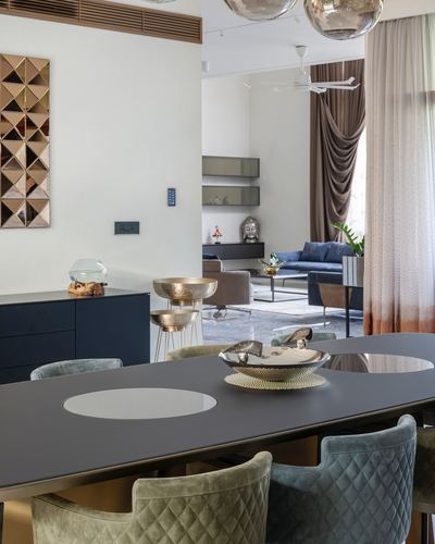 Dining table with mirrored inlay and velvet chairs opens to a living room beyond