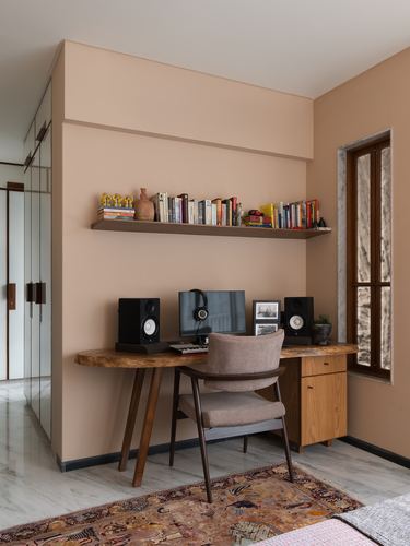 Home study nook with terracotta wall, floating bookshelf, wooden desk and cane-back chair