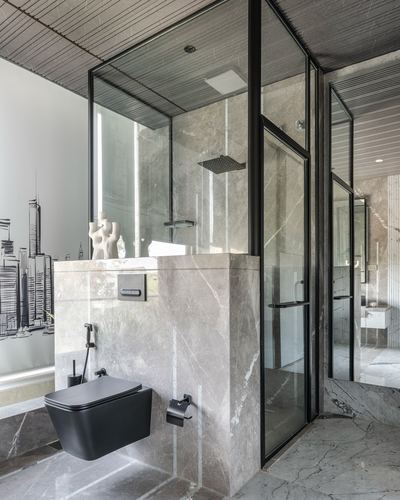 Marble bathroom with black-framed glass shower, wall-mounted black toilet, and skyline mural