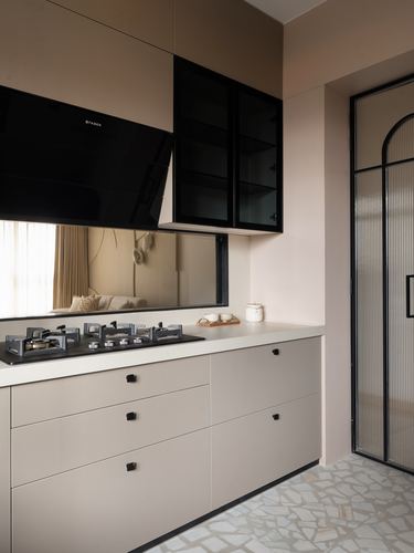 Taupe kitchen with black chimney hood, glass cabinets, mirrored backsplash and stone countertop