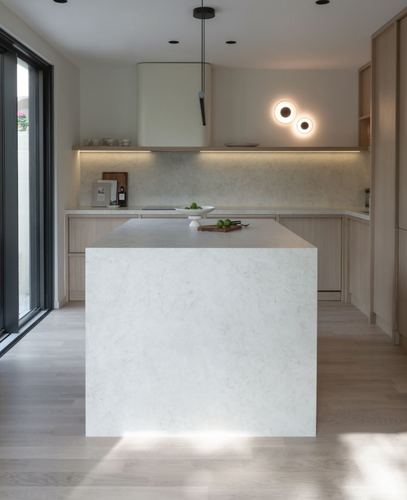 Minimalist kitchen with stone waterfall island, wood cabinetry, and round wall sconces beside a glass door