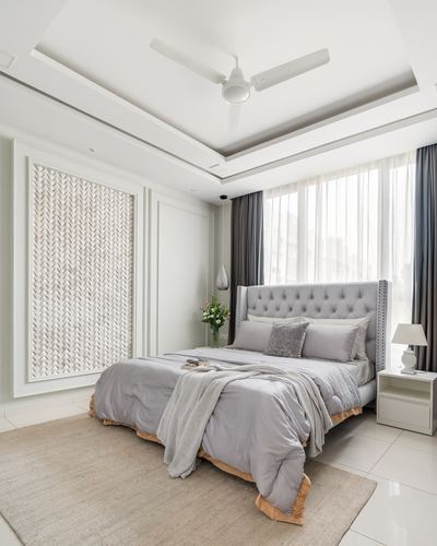 Grey tufted bed in soft neutral bedroom with woven textured wall panel and tray ceiling