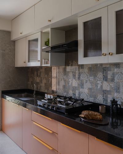 Galley kitchen with terracotta cabinets, black stone counter, patterned tile backsplash and gas hob