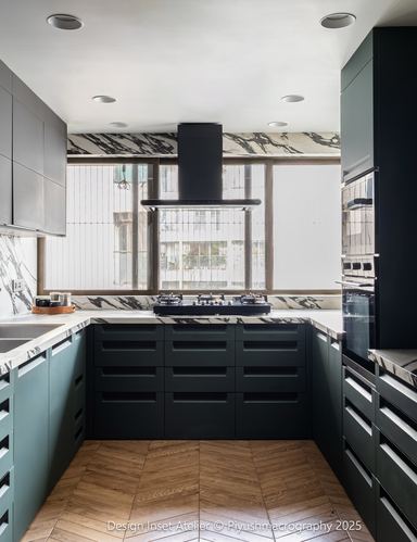 U-shaped dark kitchen with veined stone backsplash and chevron wood floor