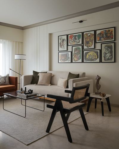 Neutral living room with beige sofa, black cane chair, and a gallery wall of framed prints