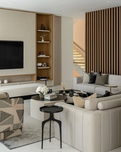Neutral living room with slatted wood wall, staircase, and layered beige seating