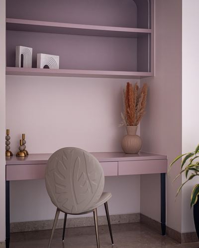 Mauve study nook with open shelving, wooden desk, and sculptural leaf-patterned chair