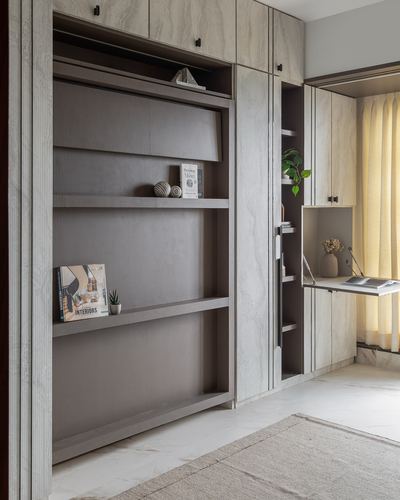 Built-in wardrobe with open bookshelf and fold-out desk beside curtained window