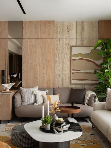 Living room with wood-panelled wall, stone accent, curved sofa, layered coffee table styling