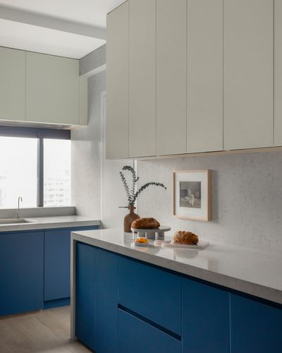 Modern kitchen with blue lower cabinets, pale upper cabinets, and stone countertop island