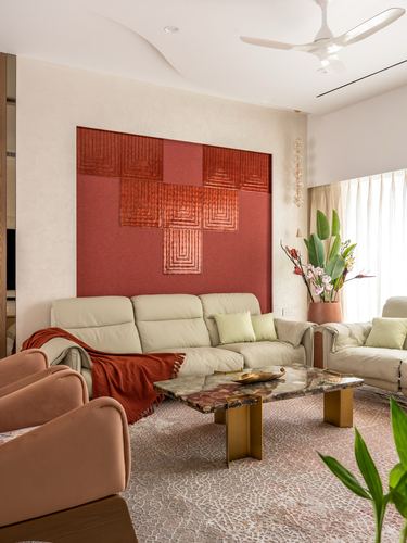 Living room with cream sofas, terracotta textured wall panel, and marble coffee table on gold legs