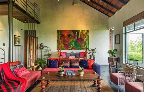 Colonial-style living room with pitched wood-beam ceiling, red textile sofas, and large portrait painting