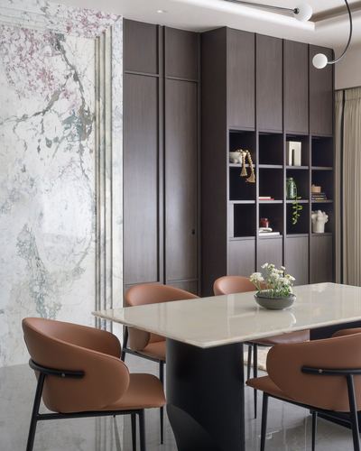 Dining table with terracotta leather chairs beside a dark wood cabinet wall and marble slab feature wall