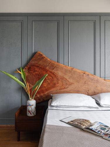 Bedroom with live-edge wood headboard against grey paneled wall, white bedding and wooden nightstand