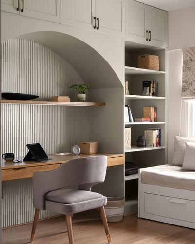Grey study nook with arched fluted panel desk and open bookshelves beside a bed