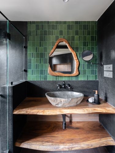 Bathroom with green textured tile, organic wood mirror, and stone vessel sink on live-edge wood counter