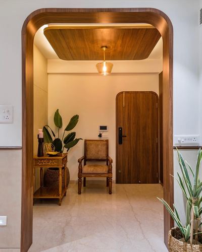Arched wooden entryway framing a foyer with pendant light, wooden door and cane chair