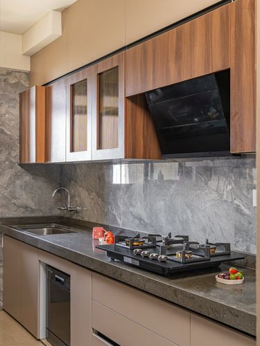 Modern kitchen with wood-panelled cabinetry, black chimney hood, and grey stone countertop and backsplash