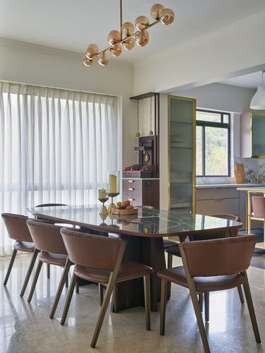 Dining room with marble table, leather chairs, and a brass globe chandelier under sheer curtains