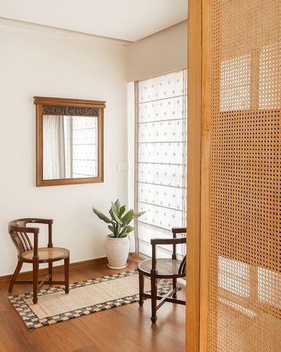 Foyer with carved mirror, cane chairs, plant, and woven cane partition door