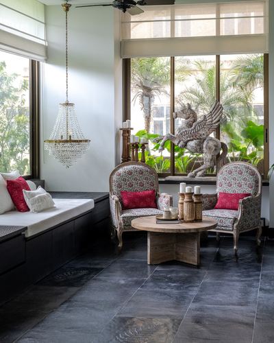 Living room nook with floral armchairs, crystal chandelier, dark stone floor and a winged horse sculpture by the window