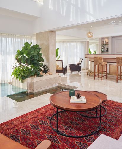 Living room with marble floor, round wood coffee tables on red rug, and built-in planter water feature