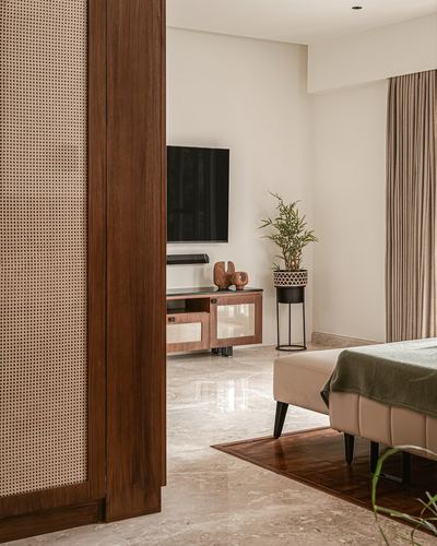 View through cane and wood door into bedroom with tv console and planter