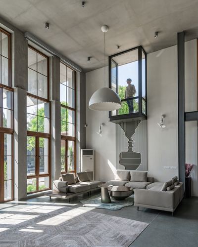 Double-height living room with tall wood-framed windows, dome pendant, sectional sofa, and mezzanine window box above.