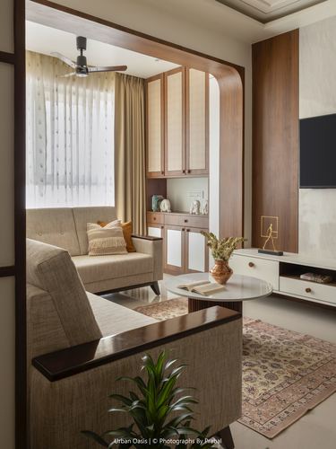 Living room with curved wooden archway, beige sofas, patterned rug, and wall-mounted tv unit
