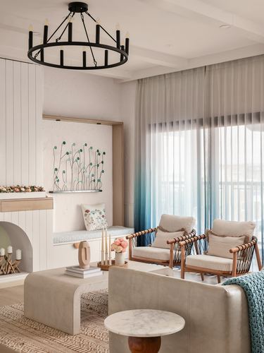 Living room with arched fireplace, window seat, cane armchairs and ombre blue curtains