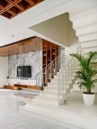 Living room with floating white staircase, marble-look tv wall, wood ceiling, and potted palm