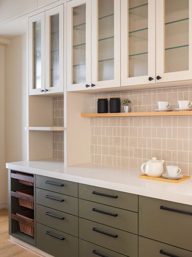 Kitchen with cream glass-front upper cabinets, olive green lower drawers, and tiled backsplash with tea set