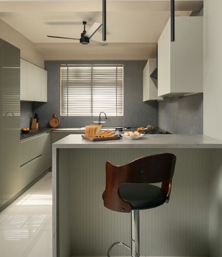 Contemporary galley kitchen with sage cabinetry, stone island counter, and a bentwood bar stool
