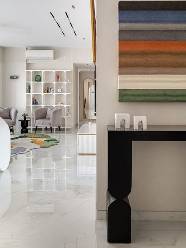 Living room with marble floor, black sculptural console, and multicolor striped wall hanging in foreground