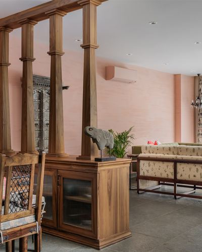 Living room with carved wooden columns, pink plaster wall, and antique door panel