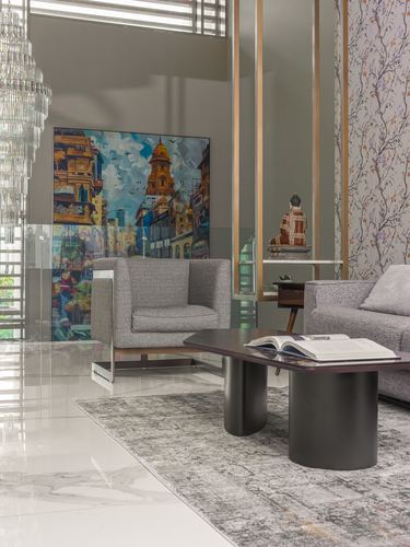 Living room corner with grey armchair, dark oval coffee table and large cityscape painting