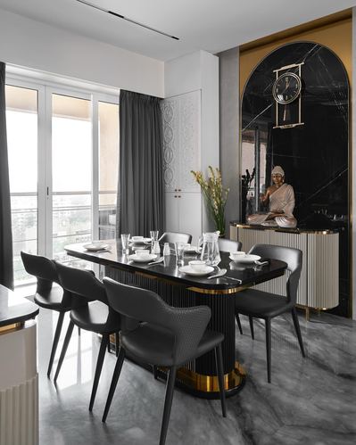 Dark marble dining room with fluted table base, grey chairs, and buddha statue in arched niche